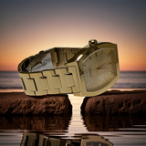 Gold wristwatch on a rock with a sunset over water background
